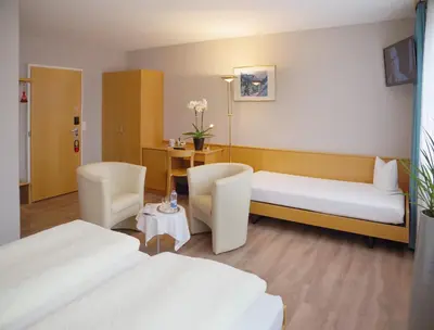 a hotel room with two beds and a table at Hotel Garni Arnegg in Arnegg