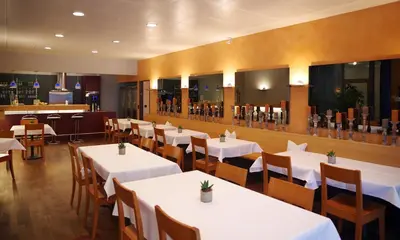 a restaurant with white tables and chairs and a bar at Hotel Garni Arnegg in Arnegg