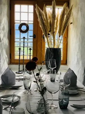 a table with glasses and vases on it with flowers at Hotel Restaurant Schlössli Sax in Sax