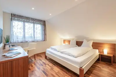 a bedroom with a large white bed and a desk at Hotel Rössli in Zuzwil