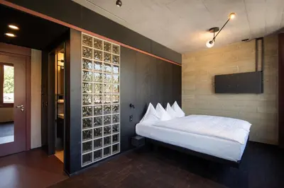 a bedroom with a white bed and a wall with wine bottles at Tailormade Hotel LEO St Gallen in St. Gallen