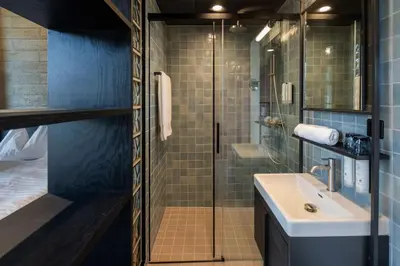 a bathroom with a sink and a glass shower at Tailormade Hotel LEO St Gallen in St. Gallen
