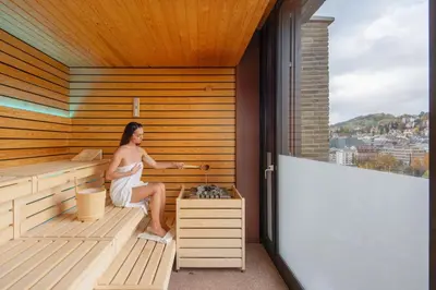 a woman is sitting in a sauna at Tailormade Hotel LEO St Gallen in St. Gallen