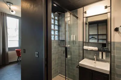 a bathroom with a sink and a glass shower at Tailormade Hotel LEO St Gallen in St. Gallen
