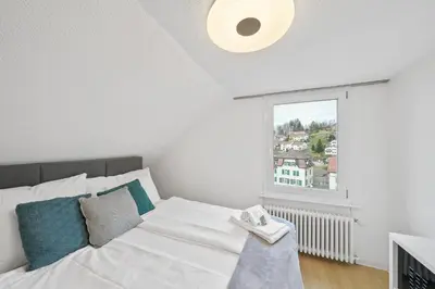 a white bed in a room with a window at book2stay - Apartments Herisau in Herisau