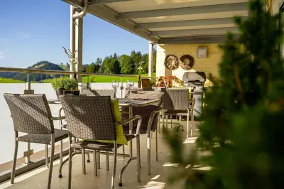a patio with tables and chairs on a balcony at Gästehaus Aemisegg in Sankt Peterzell