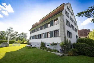 a large white building with a grass yard at Schloessli Herrenhof in Herrenhof