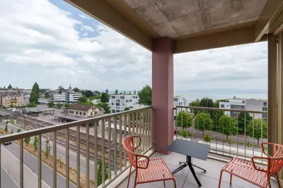 a balcony with chairs and a table and a view of a city at b-smart hotel Arbon in Arbon