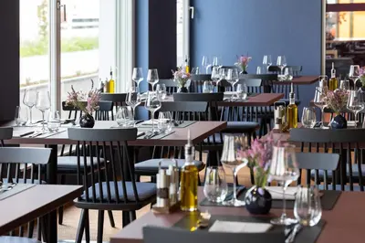 a restaurant with tables and chairs and a bar at b-smart hotel Arbon in Arbon