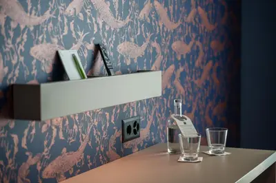 a table with two glasses and a bottle on a wall at b-smart hotel Arbon in Arbon