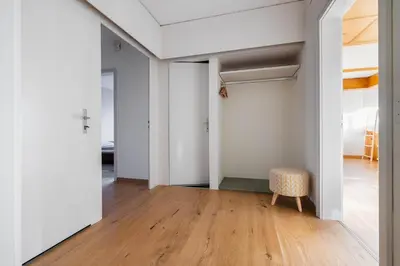 a room with white walls and a chair and wood floors at Luxury apartment with terrace and garden free parking smart TV etc in St. Gallen