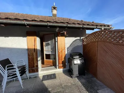 a grill on a patio next to a house at Blässchopfhüsli in Nesslau