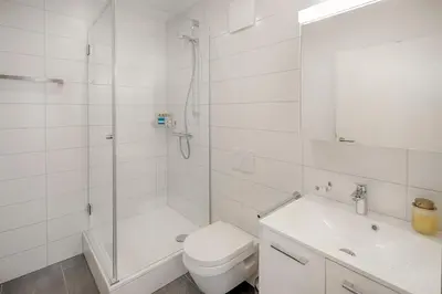 a white bathroom with a shower and a toilet and a sink at VISIMO Apartments St Georgen-Strasse St Gallen - Design City Nature in St. Gallen