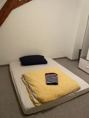 a bed with a yellow blanket on top of it at Central Room with amazing view in St. Gallen