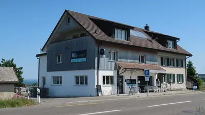 a large wooden building on the side of a street at MBar in Altnau