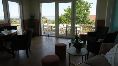 a living room with chairs and tables and large windows at MBar in Altnau