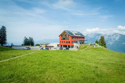 a large building on a hill with a green field at Hotel Restaurant Berghaus Malbun Buchserberg in Buchs