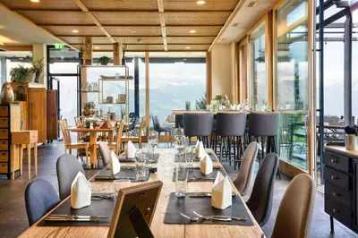 a dining room with tables and chairs and windows at Hotel Restaurant Berghaus Malbun Buchserberg in Buchs
